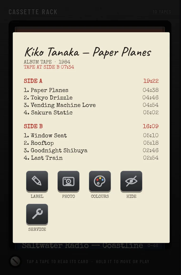 The J-card of Kiko Tanaka, Paper Planes: album tape, 1984, tape at side B, side A and side B song lists with lengths, and the keys LABEL, PHOTO, COLOURS, HIDE and SERVICE.